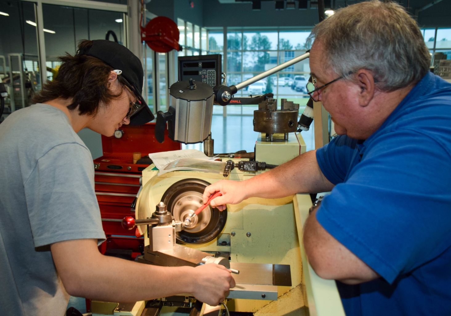 Étudiants en technologie de fabrication - Machine à tour Manufacturing and technology students working carefully with a lathe machine in a workshop.