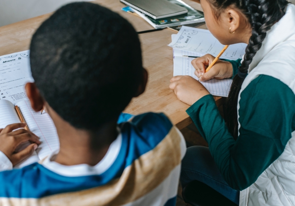 Young students doing schoolwork at the table together.