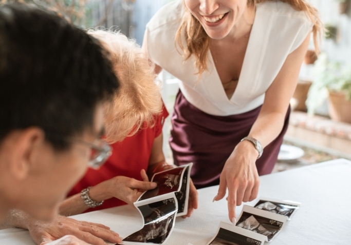 A group of three reviewing images from a sonogram in excitement!