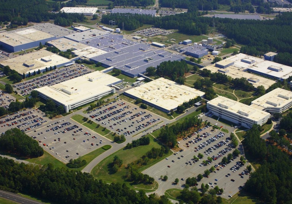 A wide aerial view of RTP with various facilities and parking lots amongst trees and greenery.