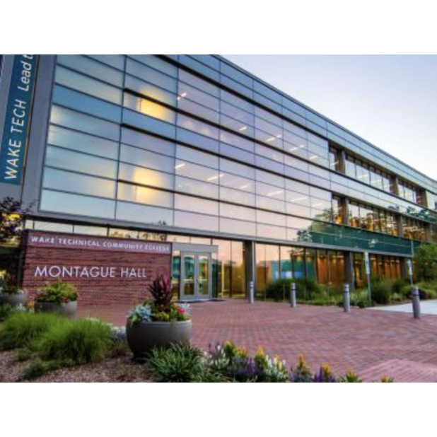 Front of the Montague Hall at Wake Tech. The building's glass front is reflecting a sunset.